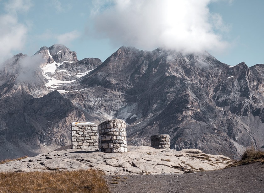 Le sommet d'une passe alpine, avec en fonds des sommets rocailleux gris.