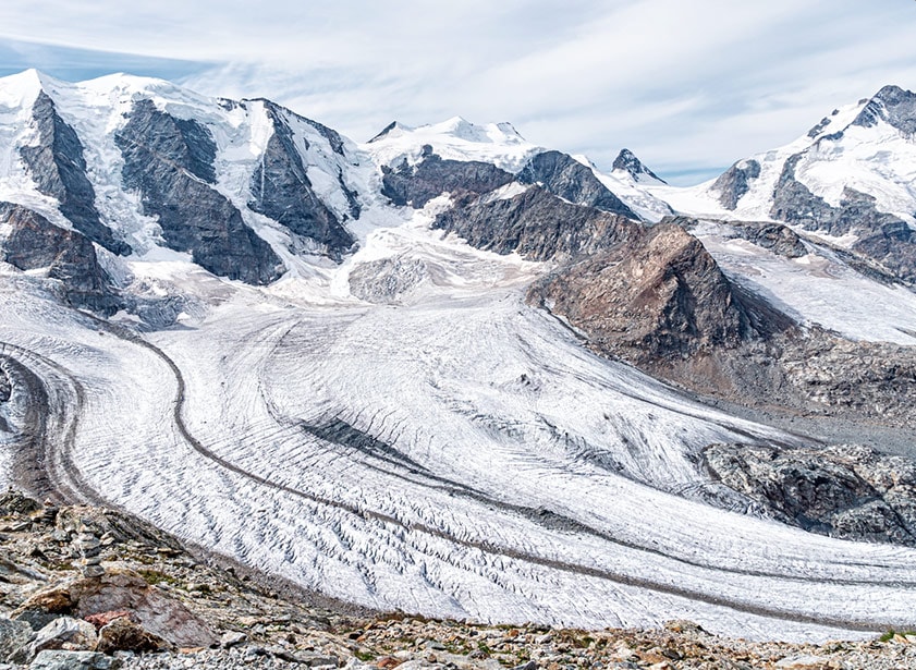 Un grand glacier alpin, avec des sommets enneigés en fond.