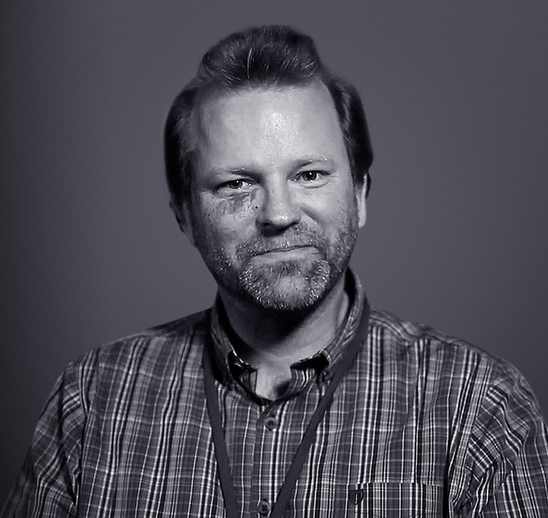 Black and white portrait of Ronald Menzel, wearing a striped shirt.